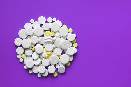 Yellow and white tablets scattered on a violet medical table, background, copy spaceの写真素材