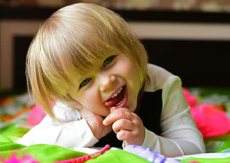 Little smiling girl lying on the bed