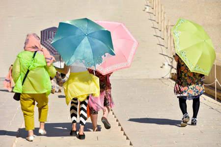 Tourists hide under umbrellas from the sun while traveling, hot, sunの写真素材