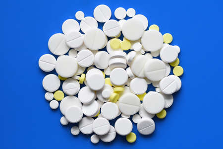Yellow and white tablets scattered on a blue medical table, background, copy spaceの写真素材