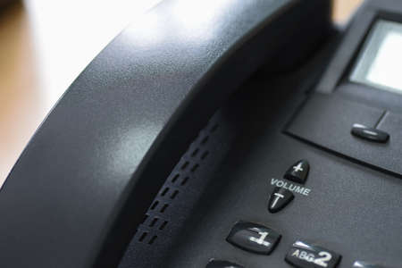 Close-up of a black digital office phone on a deskの写真素材
