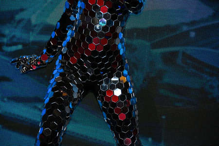 Girl with a slender figure in a fantastic mirror suit with a mask of mirrors performing in the arenaの写真素材