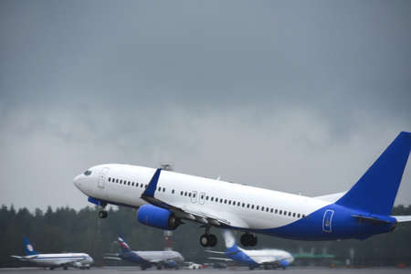 Passenger liner takes off into sky from the airport runway in cloudy weather with rain