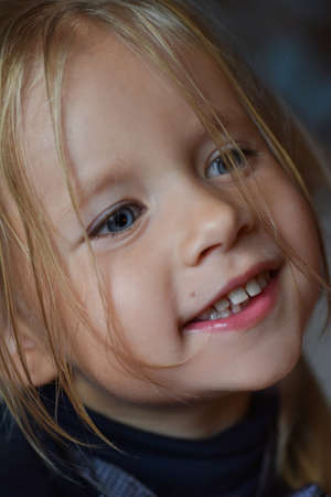 Portrait of joyful romantic little girl with big blue eyes and an open smile from Eastern Europe,...