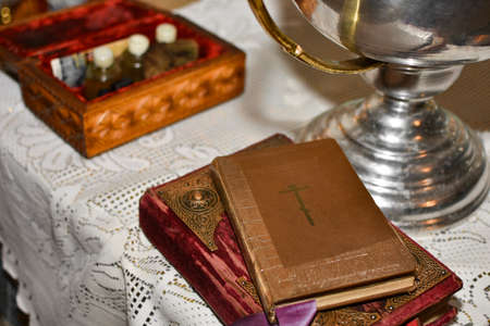 Bible lies on the table with the cup in the church before the rite of baptism