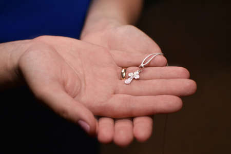 Orthodox cross in the hands of woman mother during baptism, concept hope, close-up