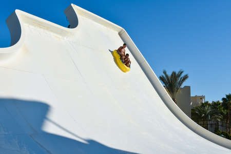 Family of dad and son ride a tubing on a fast water attraction in an aquapark