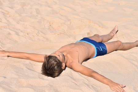 Teen lies in the sand on sea beach, angelの写真素材