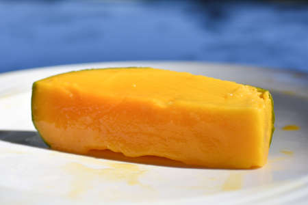 Cut juicy mango fruit in plate on the beach