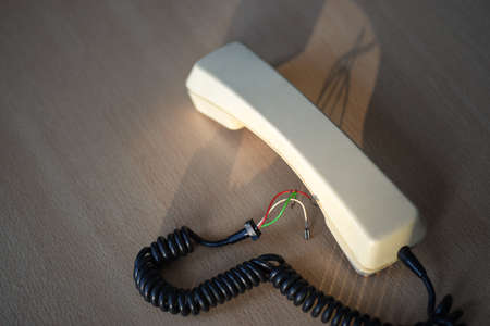 Old handset with a torn wire on office deskの写真素材