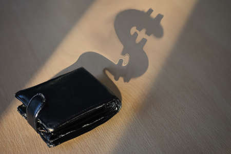The shadow of black wallet dollar form on the office desk