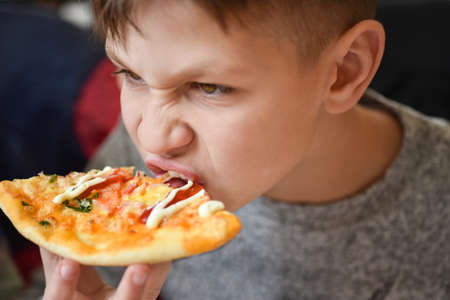 Hungry teenager eats pizza at pizzeria.の写真素材