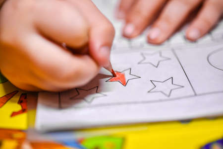 Child learns to draw, a girl paints a star figure with a pencilの写真素材