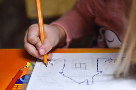Child preschooler learns to draw and write in notebooks at home in the evening under the light from desk lampの写真素材