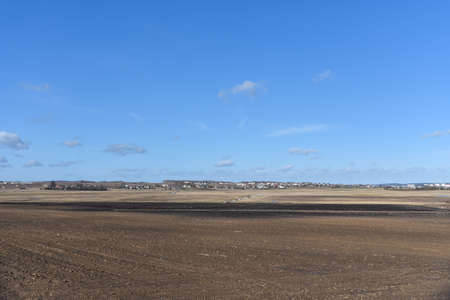 Spring farm field without vegetation near the village.