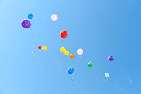 Colored balloons fly in the blue sky.