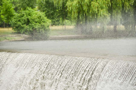 Splashes of a waterfall on a river in a city park.
