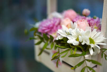 Bouquet of flowers in a wooden basket on the window.の写真素材