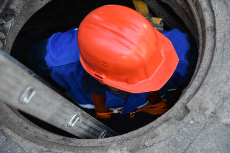 Worker in a helmet descends into a cable well.の写真素材