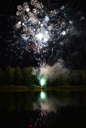 People fire salute near the lake at night.