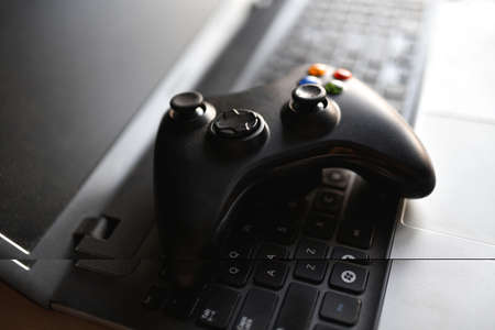 Game joystick lies on a black laptop.