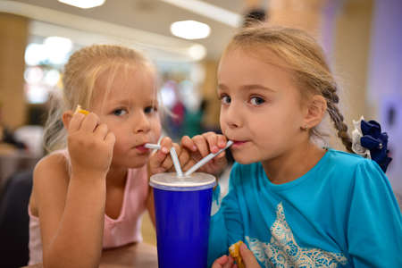 Two girls laughing and drinking a cocktail in a cafe.の写真素材
