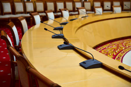 Round table with microphones for diplomatic negotiations in the hall.の写真素材