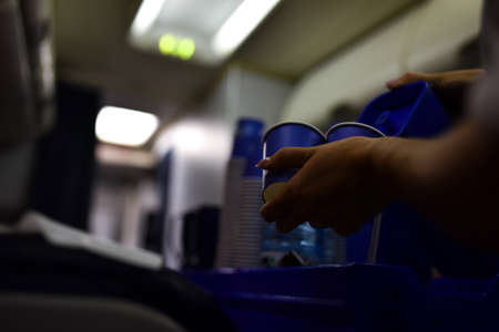 Stewardess on a plane gives drinking water to a passenger.