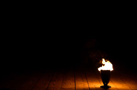 Fire in a lamp on a wooden floor on a black background.の写真素材