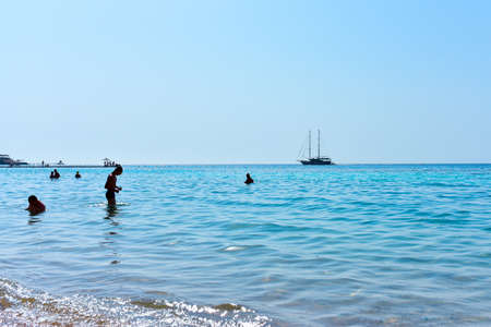 The yacht floats along the beach by sea.