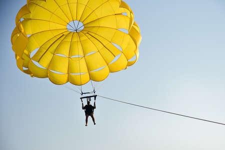 A man flies a parachute over the sea at sunset.の写真素材