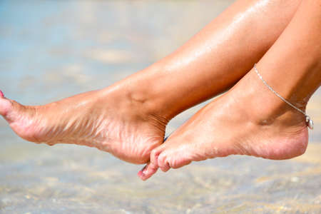 Beautiful feet of a girl over sea water on the shore.