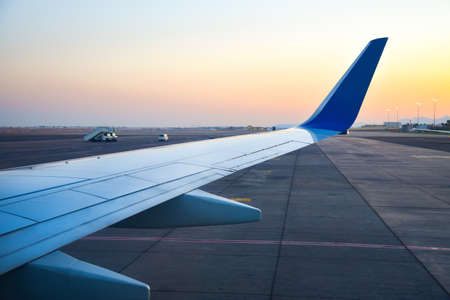 Airplane wing on the runway in the evening.
