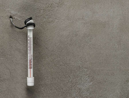 Thermometer hanging on a wall in the street in severe frost.