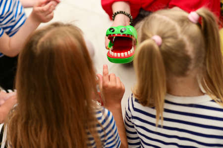 Children at a party play a game to remove a hand from the mouth of a crocodile.の写真素材