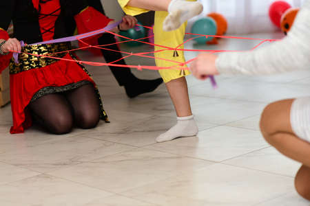 Children at a party play a game jumping over a rope with a bell.の写真素材