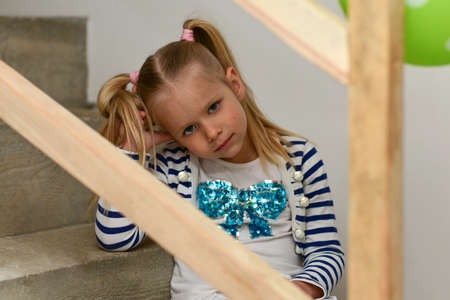 Girl sitting on concrete stairs with wooden railing.