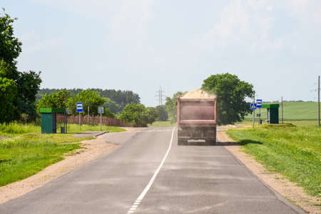 A truck carries sand and spills on the road.