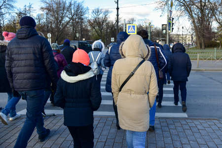 A group of people cross the crosswalk in the city, autumn.