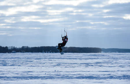 Snowboarders on the parachute ride on the frozen lake.の写真素材