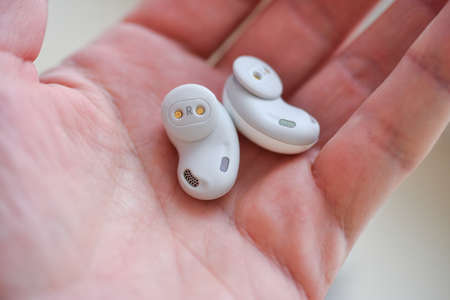 Wireless white in-ear headphones in hand, isolate.