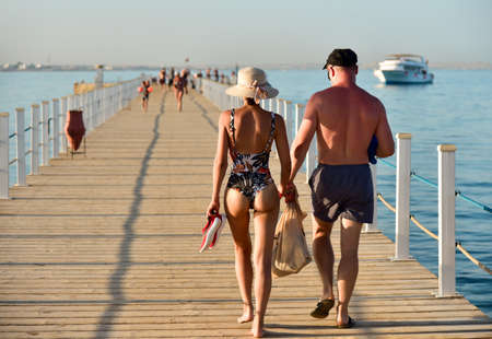 A couple of people walking on a pier in swimsuits watching and snorkeling.の写真素材