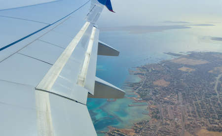 Airplane wing on the background of the blue sea with corals.