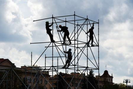 Builders assemble a stage in a city from a metal frame.