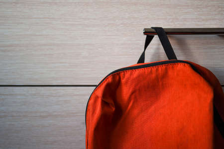 Bright orange school backpack hanging on the shelf.の写真素材
