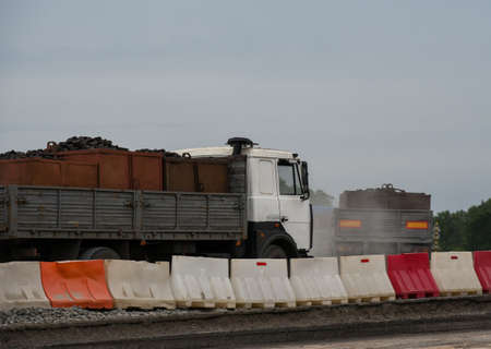 Trucks carrying cargo along a road under construction.の写真素材