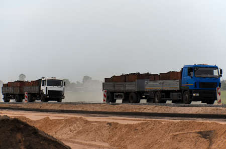 Trucks carrying cargo along a road under construction.の写真素材