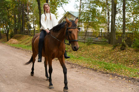 Young girl walking with a horse in nature.