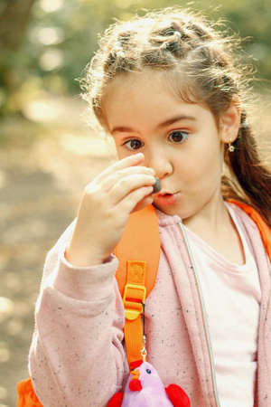 Walking girl in a pink jacket with an orange backpack in the autumn forest