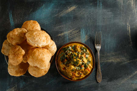 indian food curry in brown dish with bengali puff flatbread luchi on wooden table top view with copy spaceの写真素材